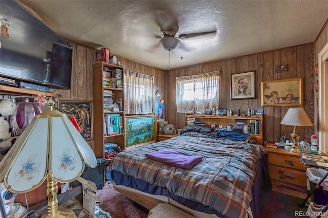 bedroom with ceiling fan, wooden walls, and a textured ceiling