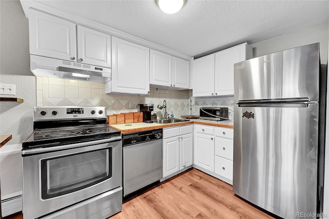 kitchen with light wood-type flooring, stainless steel appliances, a baseboard heating unit, sink, and white cabinetry