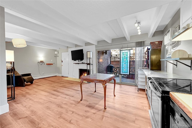 kitchen with a baseboard heating unit, white cabinets, a brick fireplace, light hardwood / wood-style floors, and beam ceiling