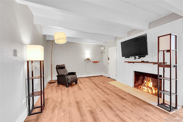 sitting room with a warm lit fireplace, wood finished floors, baseboards, baseboard heating, and beamed ceiling