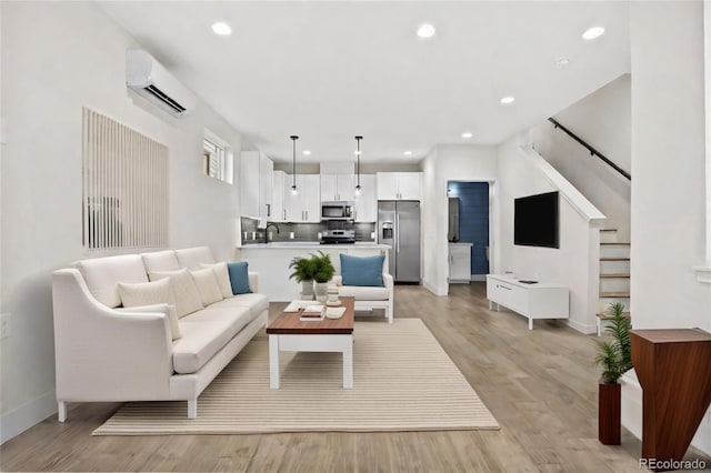 living room featuring sink, an AC wall unit, and light wood-type flooring