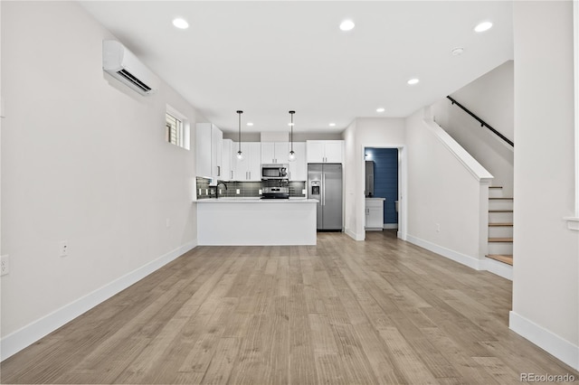 unfurnished living room with sink, a wall mounted air conditioner, and light hardwood / wood-style floors