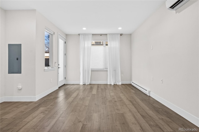 empty room featuring light hardwood / wood-style flooring, a wall unit AC, electric panel, and baseboard heating