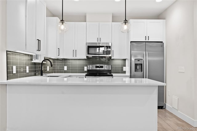 kitchen featuring white cabinetry, stainless steel appliances, and hanging light fixtures