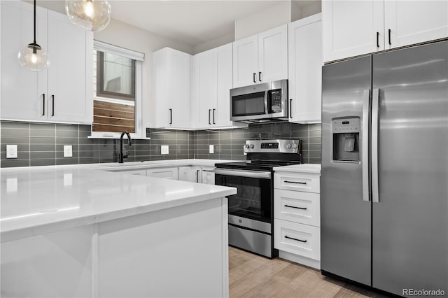 3955 W 13th Ave, Denver, CO 80204 - kitchen featuring stainless steel appliances, a sink, tasteful backsplash, hanging light fixtures, and white cabinetry