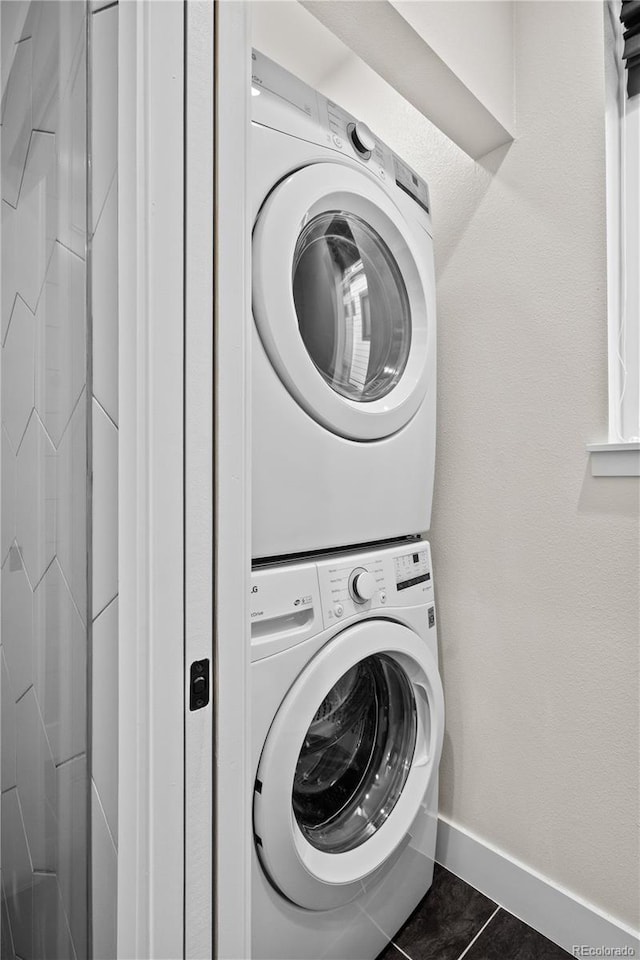 3955 W 13th Ave, Denver, CO 80204 - clothes washing area featuring baseboards, dark tile patterned floors, stacked washer and clothes dryer, and laundry area