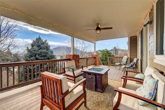 wooden terrace featuring a mountain view, an outdoor fire pit, and ceiling fan