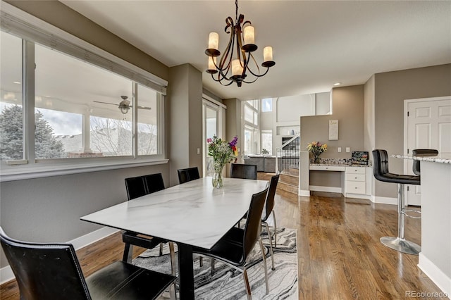 dining area with ceiling fan with notable chandelier and hardwood / wood-style flooring