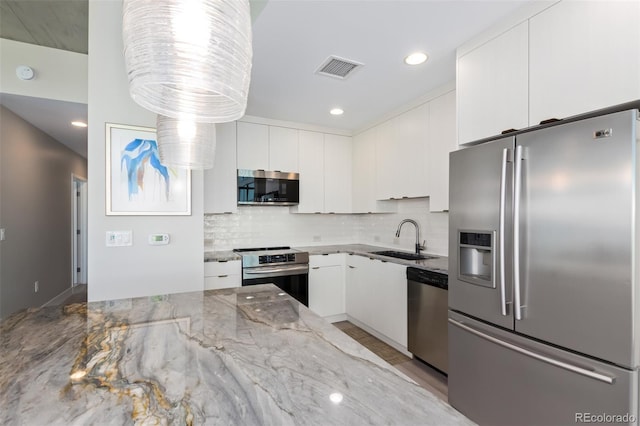 kitchen with white cabinetry, appliances with stainless steel finishes, decorative backsplash, and a sink