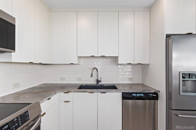 kitchen featuring stainless steel appliances, white cabinets, a sink, and decorative backsplash