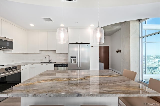 kitchen with visible vents, appliances with stainless steel finishes, a sink, a kitchen bar, and backsplash