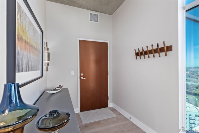 doorway to outside with light wood-type flooring, visible vents, and baseboards