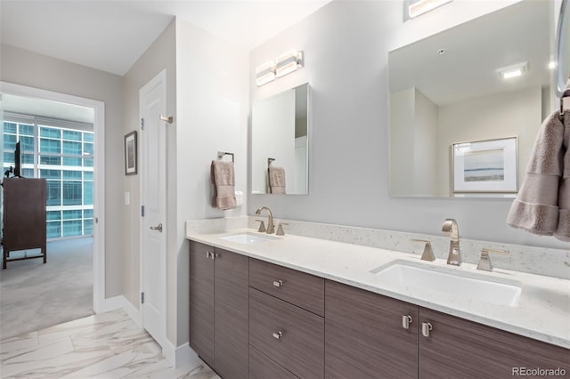 full bathroom with marble finish floor, double vanity, a sink, and baseboards