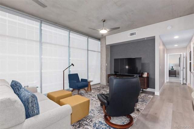 living room with baseboards, ceiling fan, visible vents, and wood finished floors