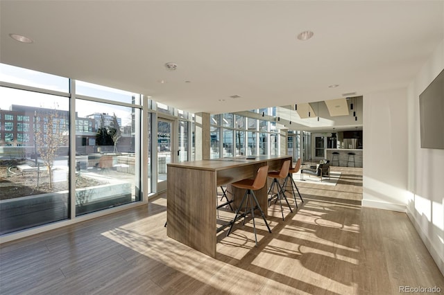 bar featuring baseboards, a view of city, floor to ceiling windows, and wood finished floors