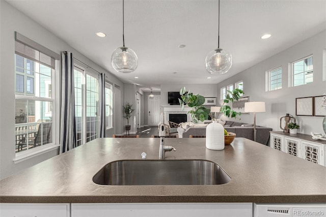 kitchen with dishwasher, sink, pendant lighting, and a kitchen island with sink