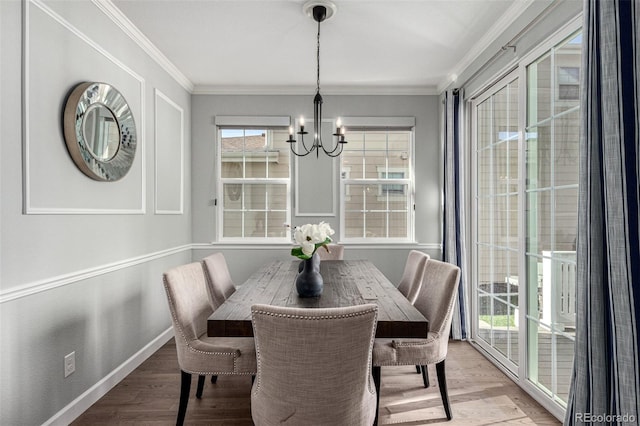 dining space with ornamental molding, hardwood / wood-style floors, and a notable chandelier