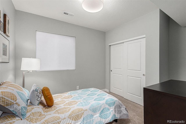 carpeted bedroom with a closet and a textured ceiling