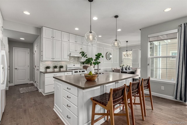 kitchen featuring hanging light fixtures, white cabinetry, a center island, and white gas range oven