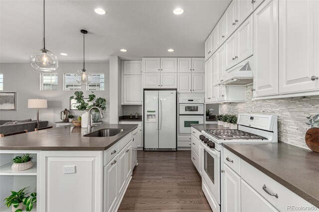 kitchen with a kitchen island with sink, sink, white appliances, and white cabinets