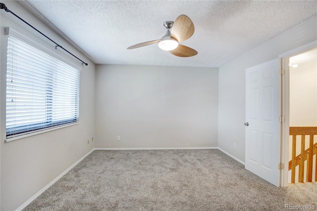 carpeted empty room with ceiling fan and a textured ceiling