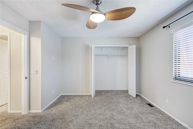 unfurnished bedroom with ceiling fan, light colored carpet, a textured ceiling, and a closet