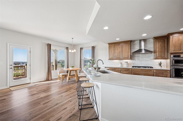 1871 Walnut Creek Ct, Colorado Springs, CO 80921 - kitchen with wall chimney range hood, double oven, gas cooktop, light countertops, and recessed lighting