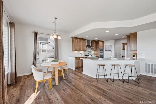 1871 Walnut Creek Ct, Colorado Springs, CO 80921 - kitchen with wall chimney range hood, double oven, dark wood-style flooring, a peninsula, and recessed lighting