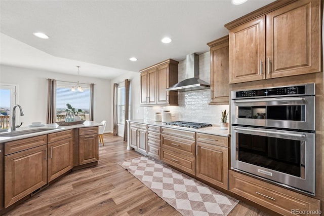 1871 Walnut Creek Ct, Colorado Springs, CO 80921 - kitchen featuring stainless steel appliances, wall chimney exhaust hood, light wood finished floors, light countertops, and decorative backsplash