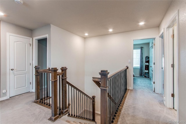 hallway featuring recessed lighting, light carpet, and an upstairs landing