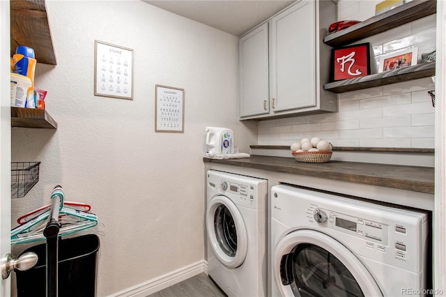 laundry area with light wood-style floors, washer and dryer, cabinet space, and baseboards