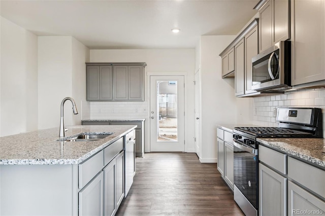 kitchen featuring appliances with stainless steel finishes, a sink, gray cabinets, light stone counters, and recessed lighting