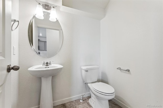 bathroom with toilet, baseboards, and a sink