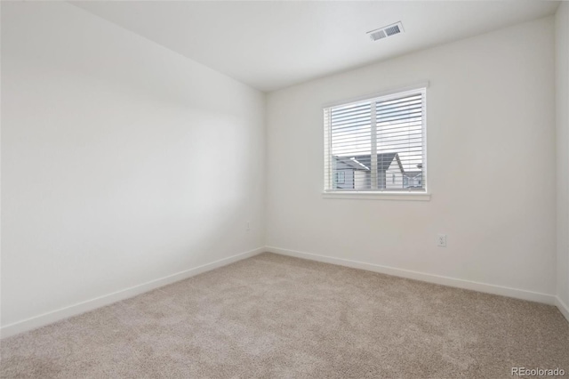 spare room featuring light colored carpet and baseboards