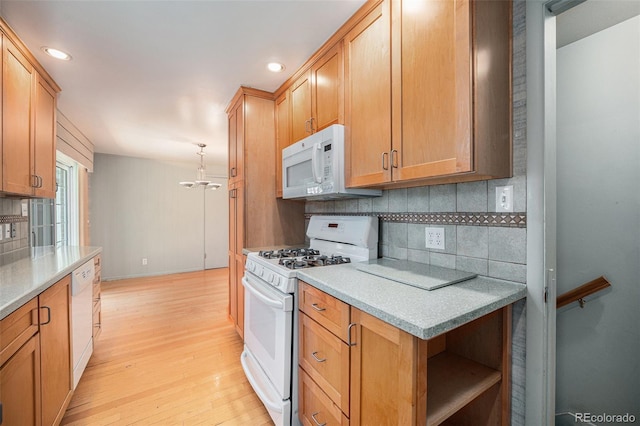 8675 W 60th Ave, Arvada, CO 80004 - kitchen featuring white appliances, tasteful backsplash, light wood-type flooring, a chandelier, and light countertops