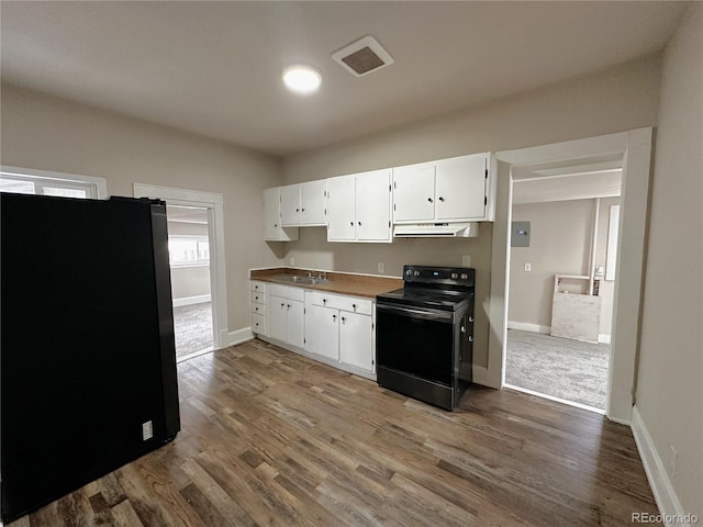 kitchen with dark wood finished floors, black electric range, freestanding refrigerator, white cabinetry, and under cabinet range hood