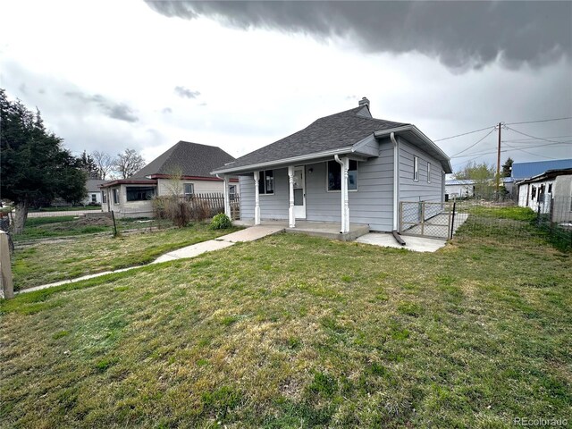 672 4th St, Limon, CO 80828 - bungalow-style house featuring fence, roof with shingles, a porch, a front yard, and a chimney