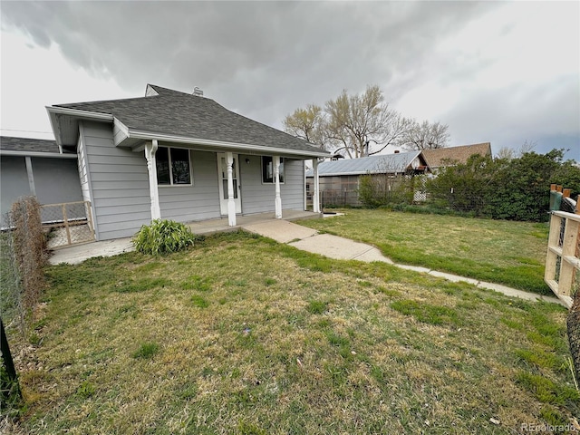 exterior space with fence, covered porch, a shingled roof, and a front lawn