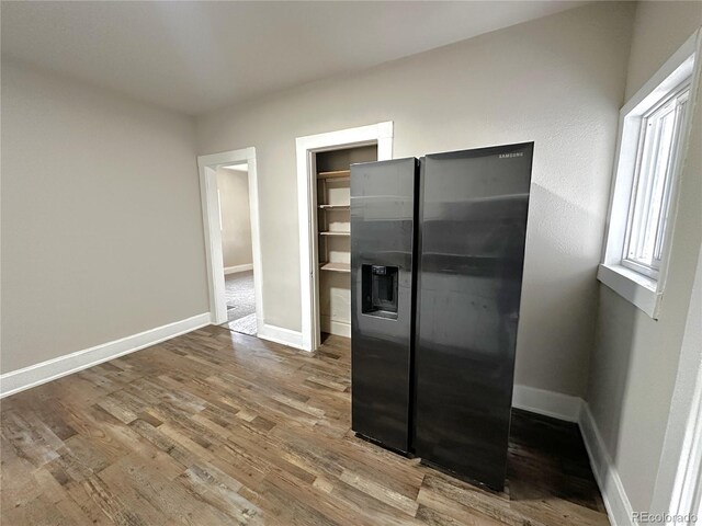 672 4th St, Limon, CO 80828 - unfurnished bedroom featuring baseboards, wood finished floors, and stainless steel fridge with ice dispenser