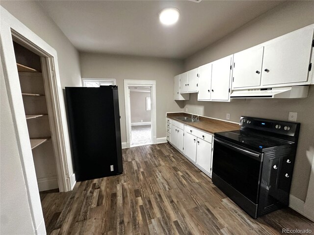 672 4th St, Limon, CO 80828 - kitchen featuring freestanding refrigerator, dark wood-style flooring, under cabinet range hood, white cabinets, and black / electric stove