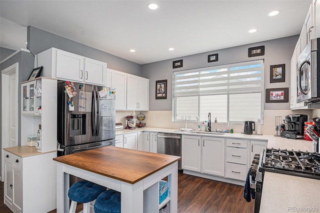 kitchen with dark hardwood / wood-style flooring, tasteful backsplash, stainless steel appliances, sink, and white cabinetry