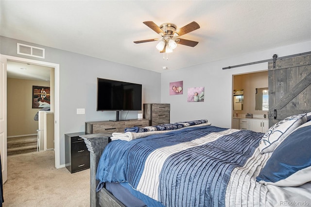 carpeted bedroom with ensuite bath, ceiling fan, and a barn door