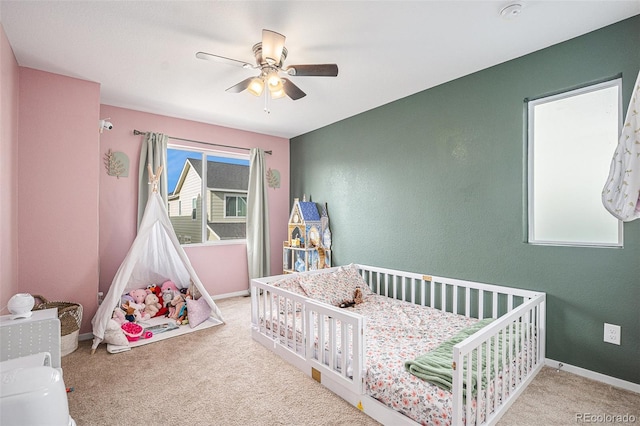 bedroom featuring ceiling fan, light carpet, and a nursery area