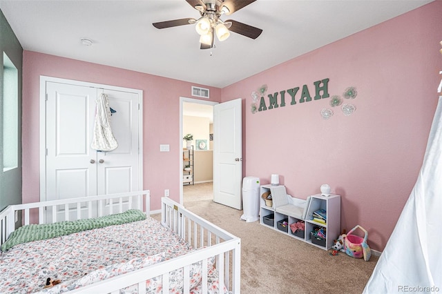 carpeted bedroom featuring a closet, a nursery area, and ceiling fan