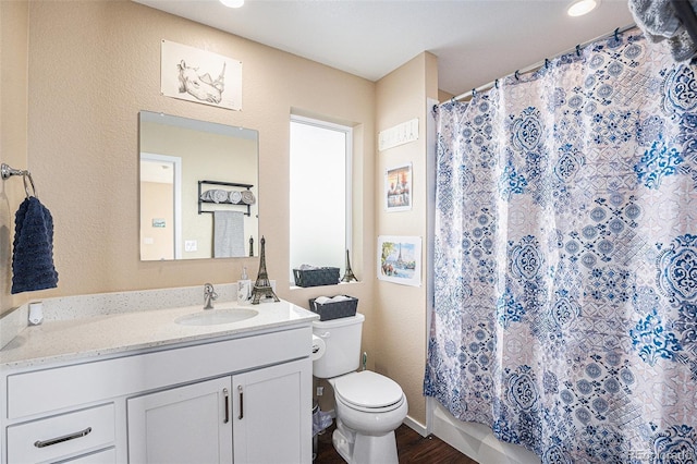 bathroom with walk in shower, hardwood / wood-style flooring, vanity, and toilet