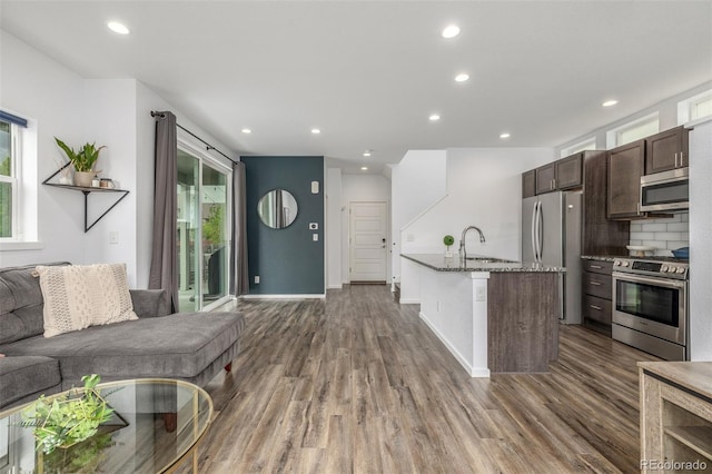 1754 W 66th Ave, Denver, CO 80221 - kitchen with stainless steel appliances, open floor plan, a sink, wood finished floors, and recessed lighting