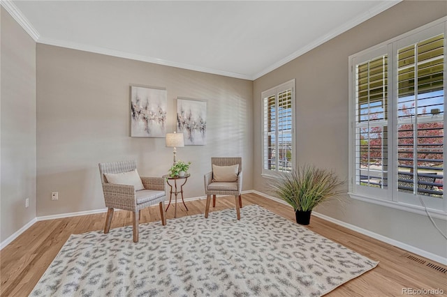 sitting room with baseboards, visible vents, ornamental molding, and wood finished floors