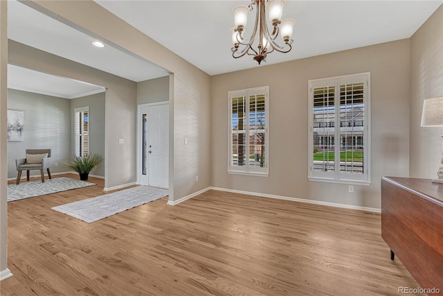 unfurnished dining area featuring plenty of natural light, baseboards, a notable chandelier, and light wood-type flooring