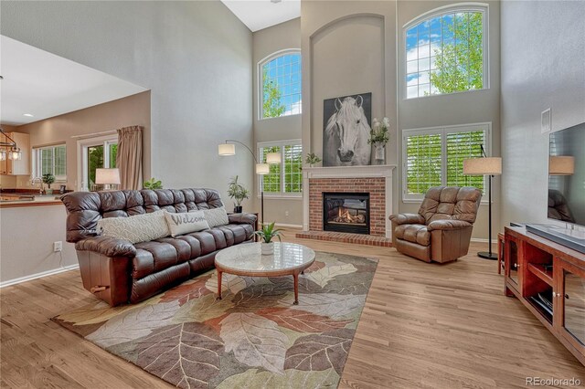living area with baseboards, a high ceiling, a fireplace, and wood finished floors