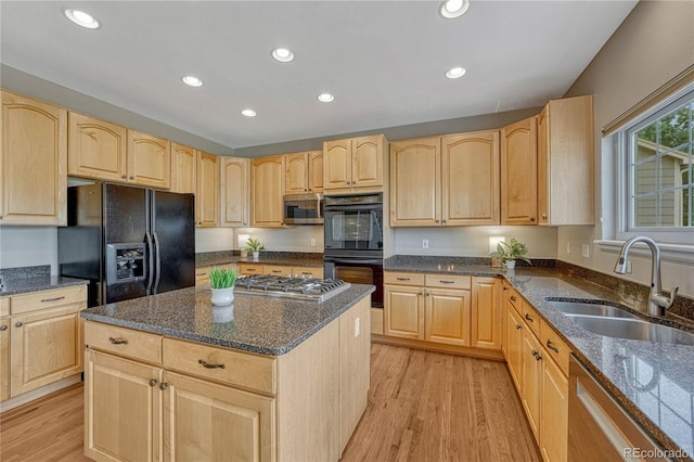 kitchen with light brown cabinetry, a sink, and black appliances